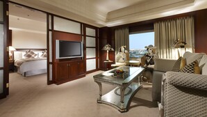 Habitación de hotel con una cama grande, televisión, mesa de centro de vidrio y vista a la ciudad.