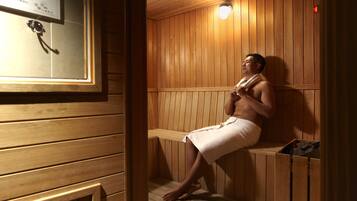 Una sauna in legno con panche, portasci e stufa a parete.
