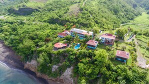 An aerial view of a coastal property with multiple houses, a swimming pool, and lush greenery. - Tamarind Tree Hotel and Restaurant (Salisbury)