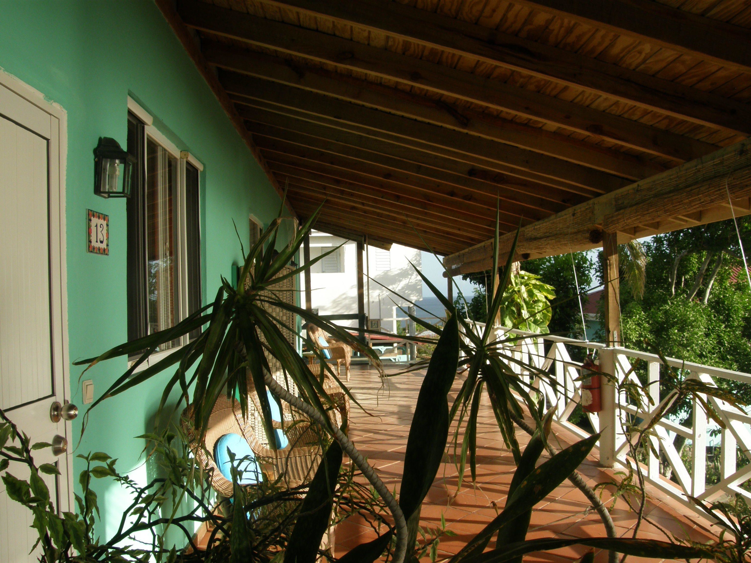 A covered porch with a tiled floor, a wooden ceiling, and a view of the ocean.
