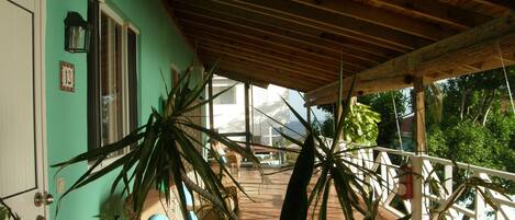 A covered porch with a tiled floor, a wooden ceiling, and a view of the ocean.