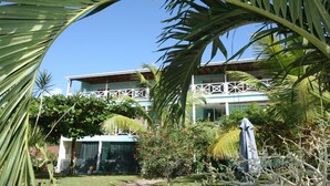 A two-story building with a balcony, surrounded by lush greenery and palm trees. - Tamarind Tree Hotel and Restaurant (Salisbury)