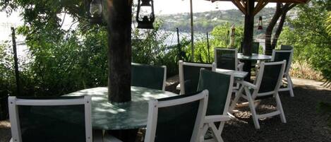 Outdoor seating with tables and chairs under umbrellas, overlooking a body of water.