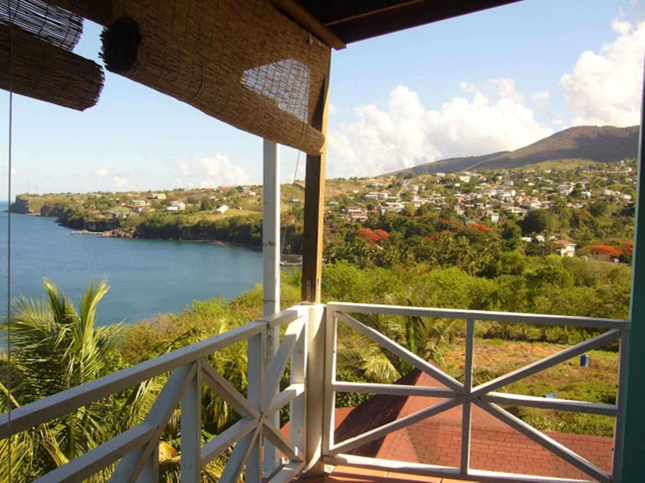 A balcony with a view of a coastal town and a mountain.