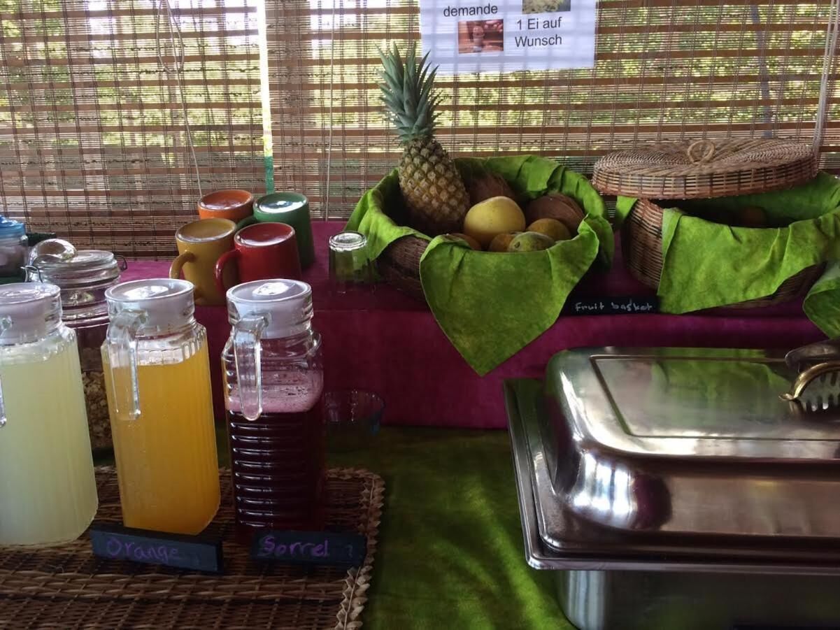 A buffet setup with various food and drink options, including a fruit basket and labeled beverage dispensers.