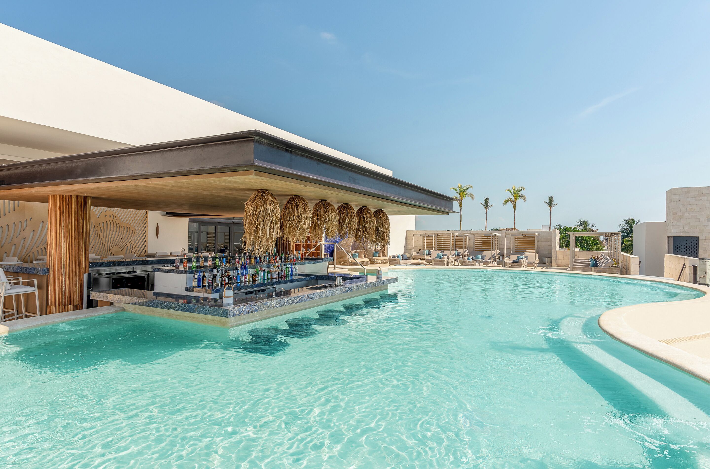 A poolside bar with a bar counter and seating area, surrounded by a pool.