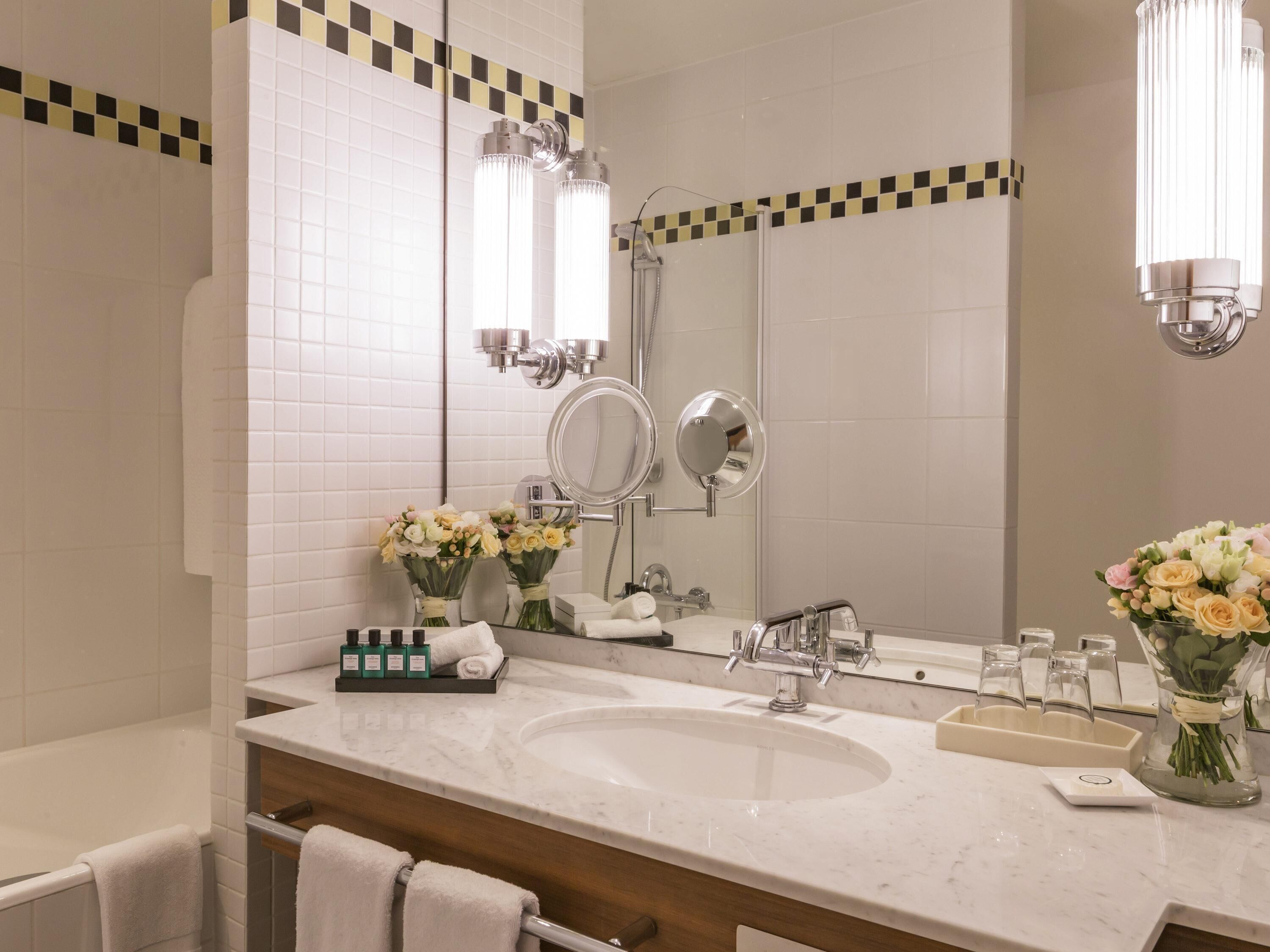 A bathroom with a large mirror, two sinks, a bathtub, and a shower.