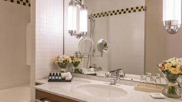A bathroom with a large mirror, two sinks, a bathtub, and a shower.