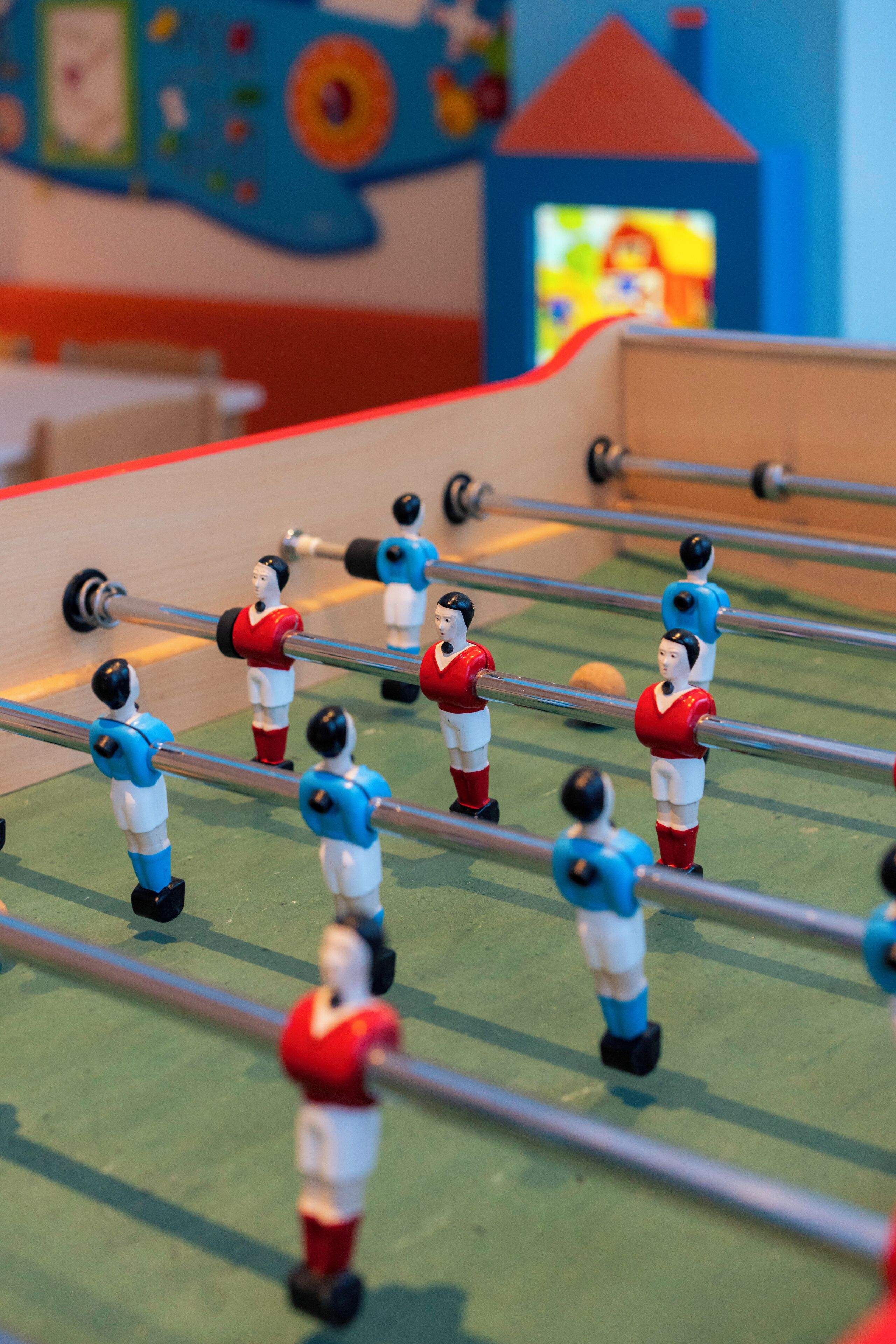 A tabletop foosball table with players in red and blue uniforms.