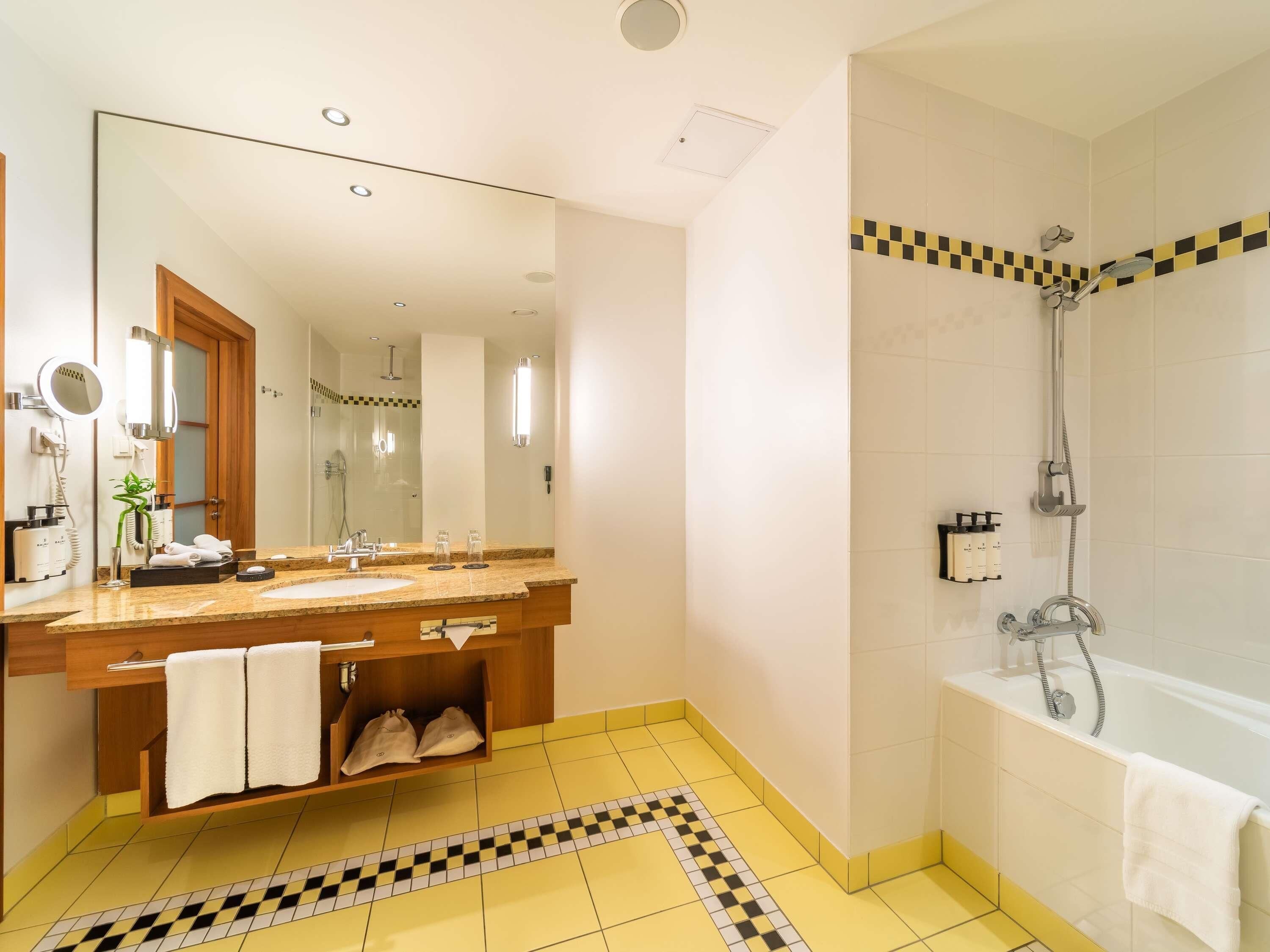 A bathroom with a sink, mirror, towel rack, shower, and a checkered floor pattern.