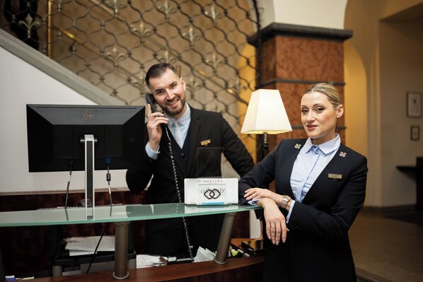 A reception desk with a nameplate, a telephone, and a lamp.