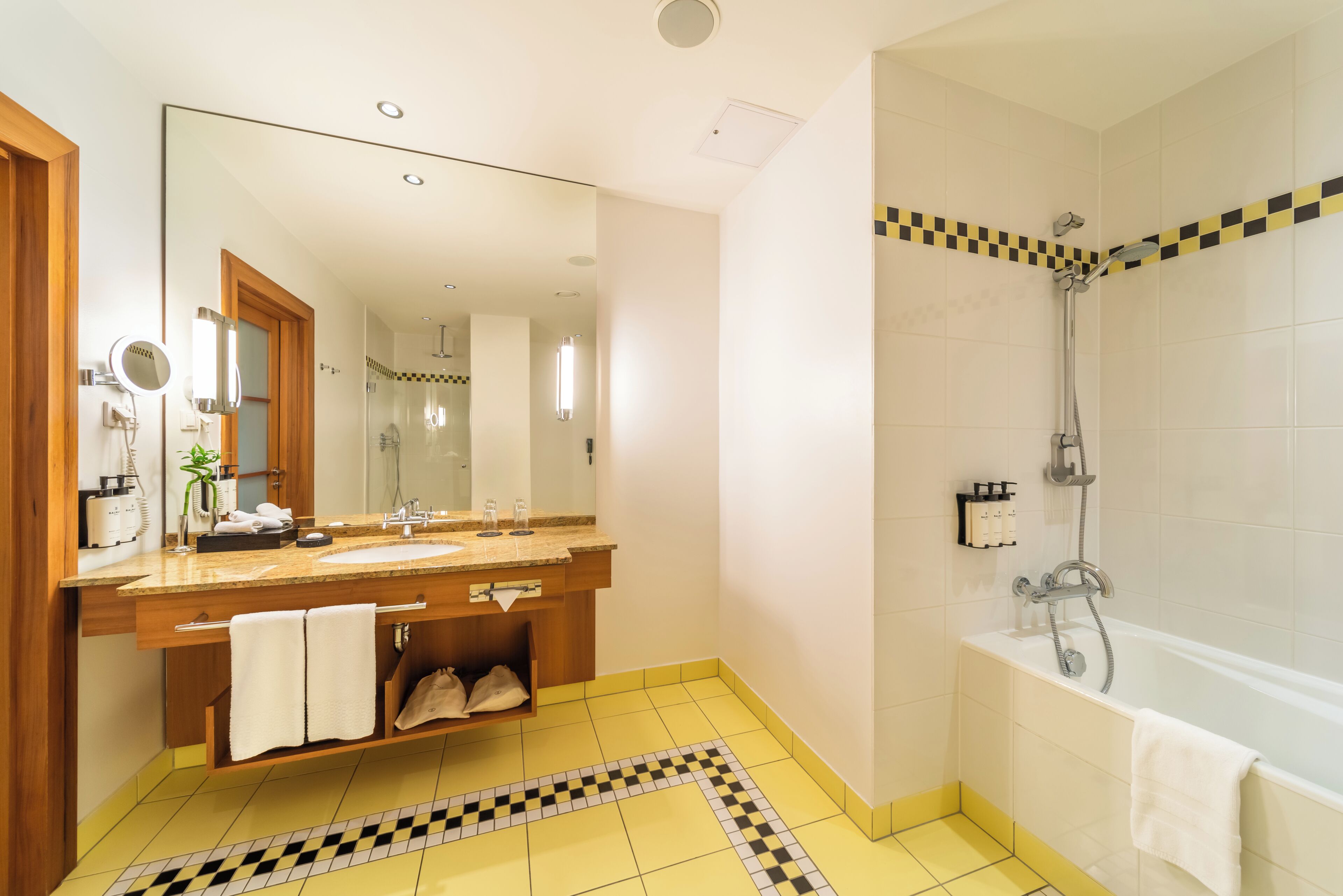 Une salle de bain avec un grand miroir, un lavabo, une douche et un sol carrelé.
