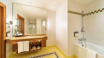 Une salle de bain avec un grand miroir, un lavabo, une douche et un sol carrelé.