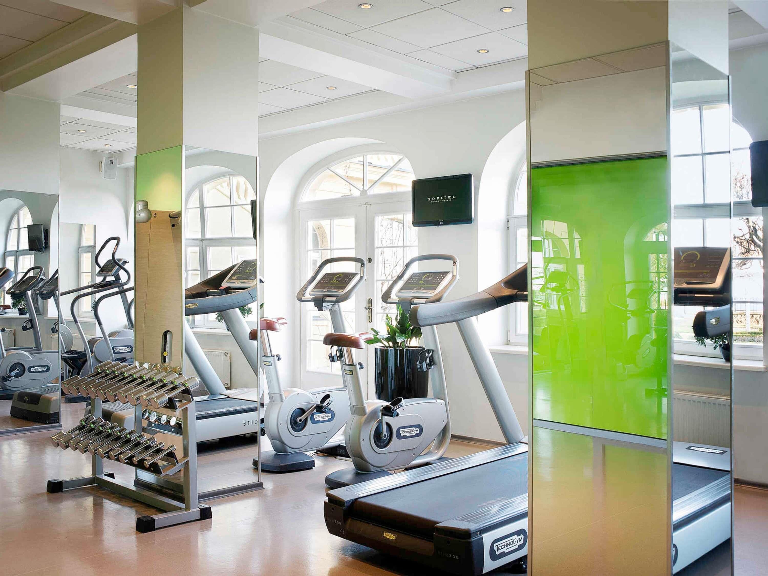 Un gimnasio con cintas de correr, bicicletas estáticas y máquinas de pesas.