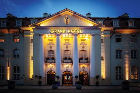 A grand hotel with a classical facade, large columns, and illuminated entrance.