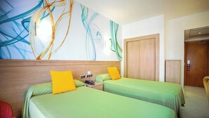A hotel room with two beds, a wooden headboard, a wall art piece, and a wooden wardrobe.