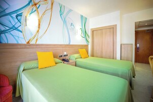 Habitación de hotel con dos camas, cabecero de madera, una obra de arte en la pared y un armario de madera.