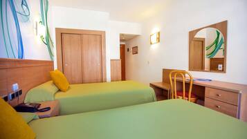 Une chambre d’hôtel avec deux lits, un bureau, une chaise, une armoire en bois et un miroir.