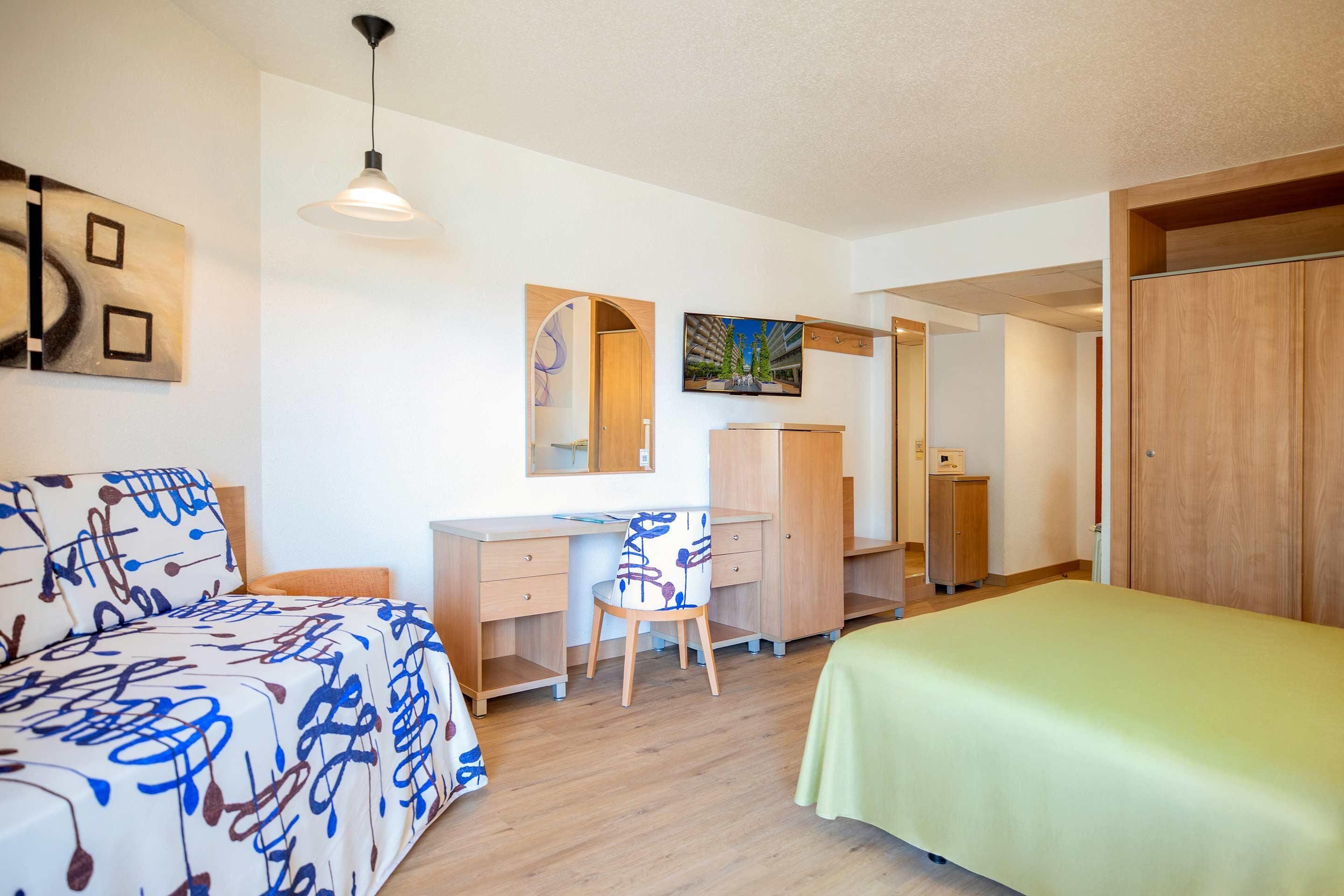 Un dormitorio con cama, escritorio, silla y armario.