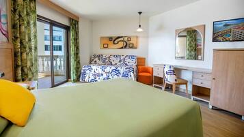 Habitación de hotel con cama, escritorio, silla, armario, una ventana grande con cortinas y un cuadro en la pared.
