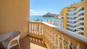 A balcony with a view of the sea and a historic building.