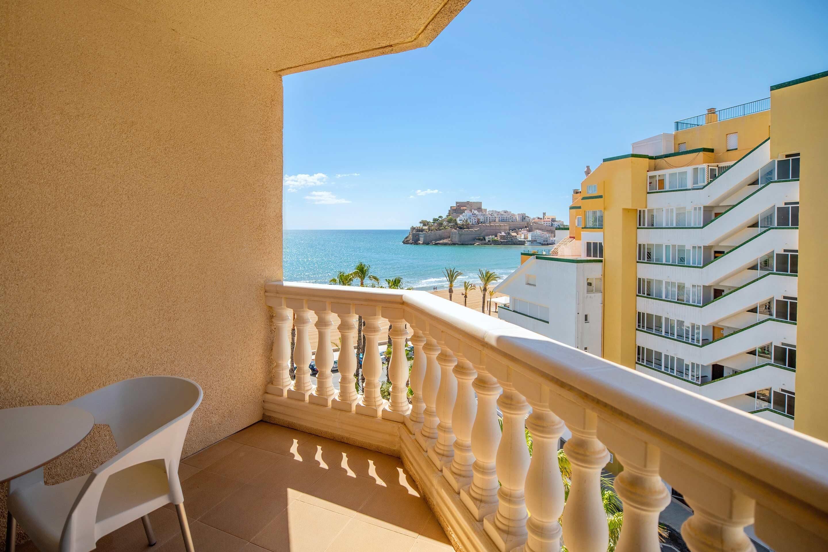 A balcony with a view of the sea and a castle-like structure on a cliff.