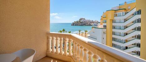 A balcony with a view of the sea and a castle-like structure on a cliff.