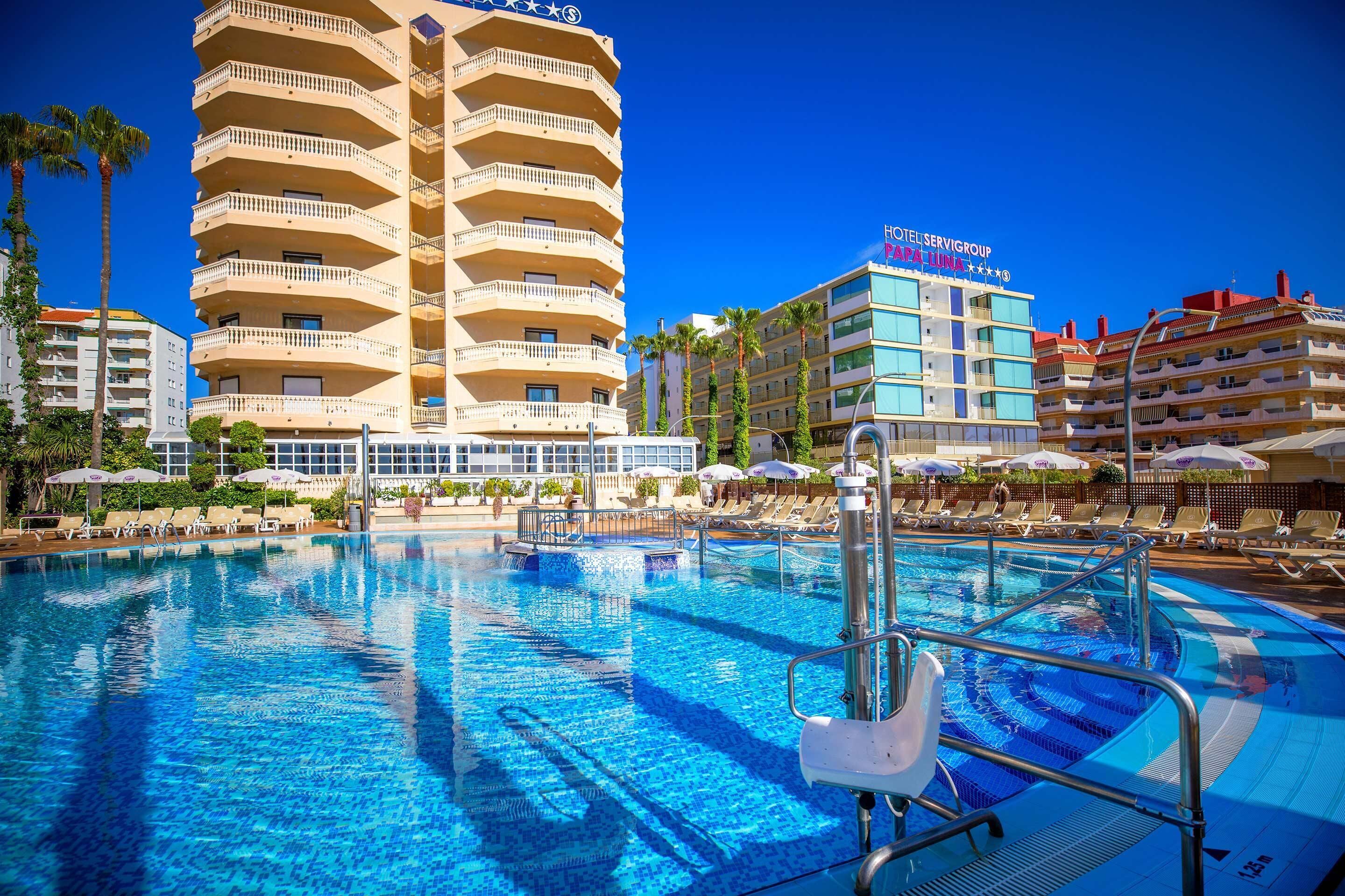 Un hotel con piscina, varios balcones y un cielo azul despejado.