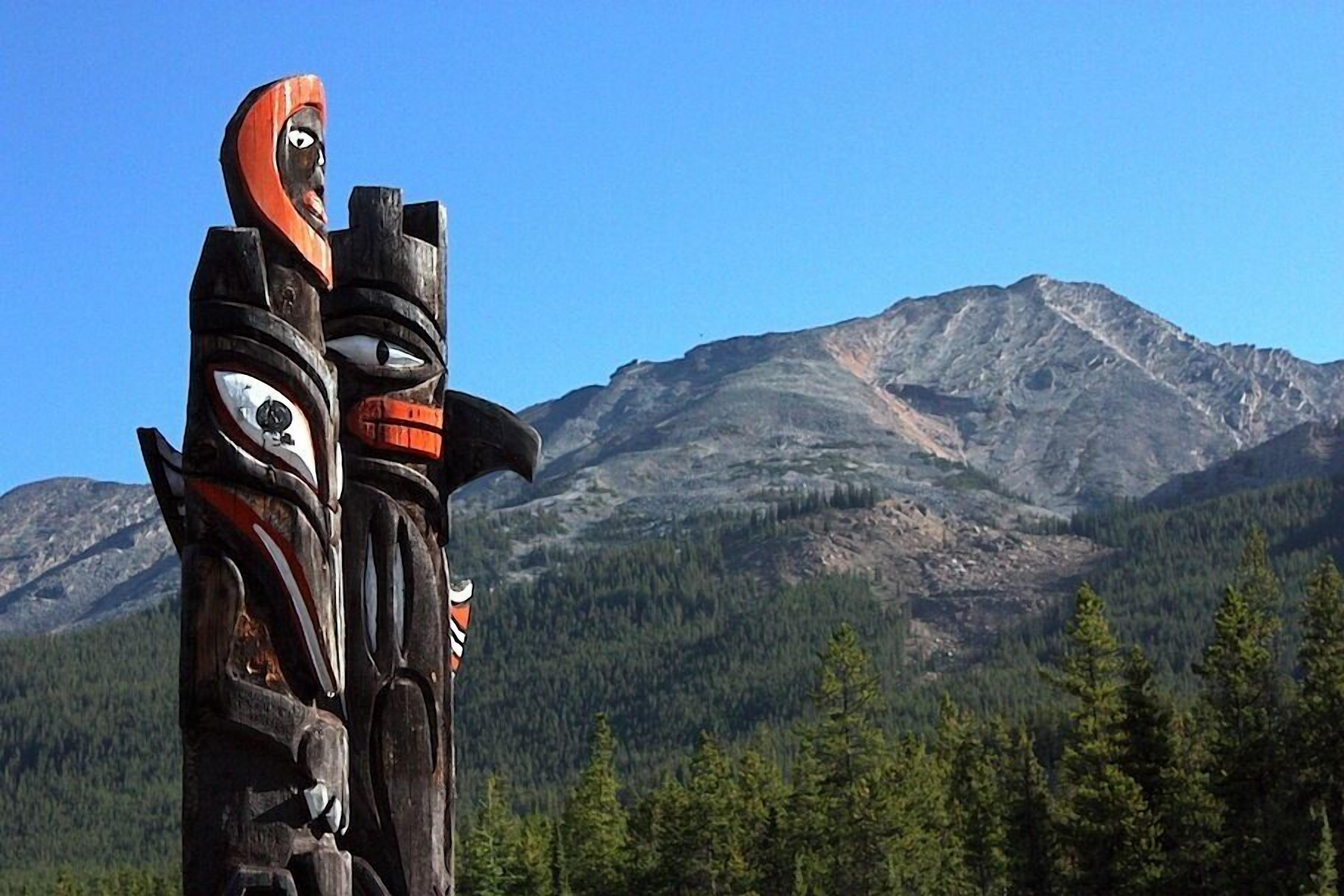 A totem pole with a mountainous background.