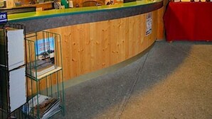 A wooden interior with a reception desk, framed pictures on the wall, and a red tablecloth.