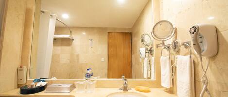 A bathroom with a sink, mirror, towel rack, and a shower area.