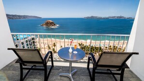 Un balcón con dos sillas y una mesa, con vista a la playa y al mar.