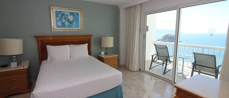A hotel room with a large bed, a wooden headboard, two bedside tables with lamps, a painting on the wall, and a balcony with a view of the sea.