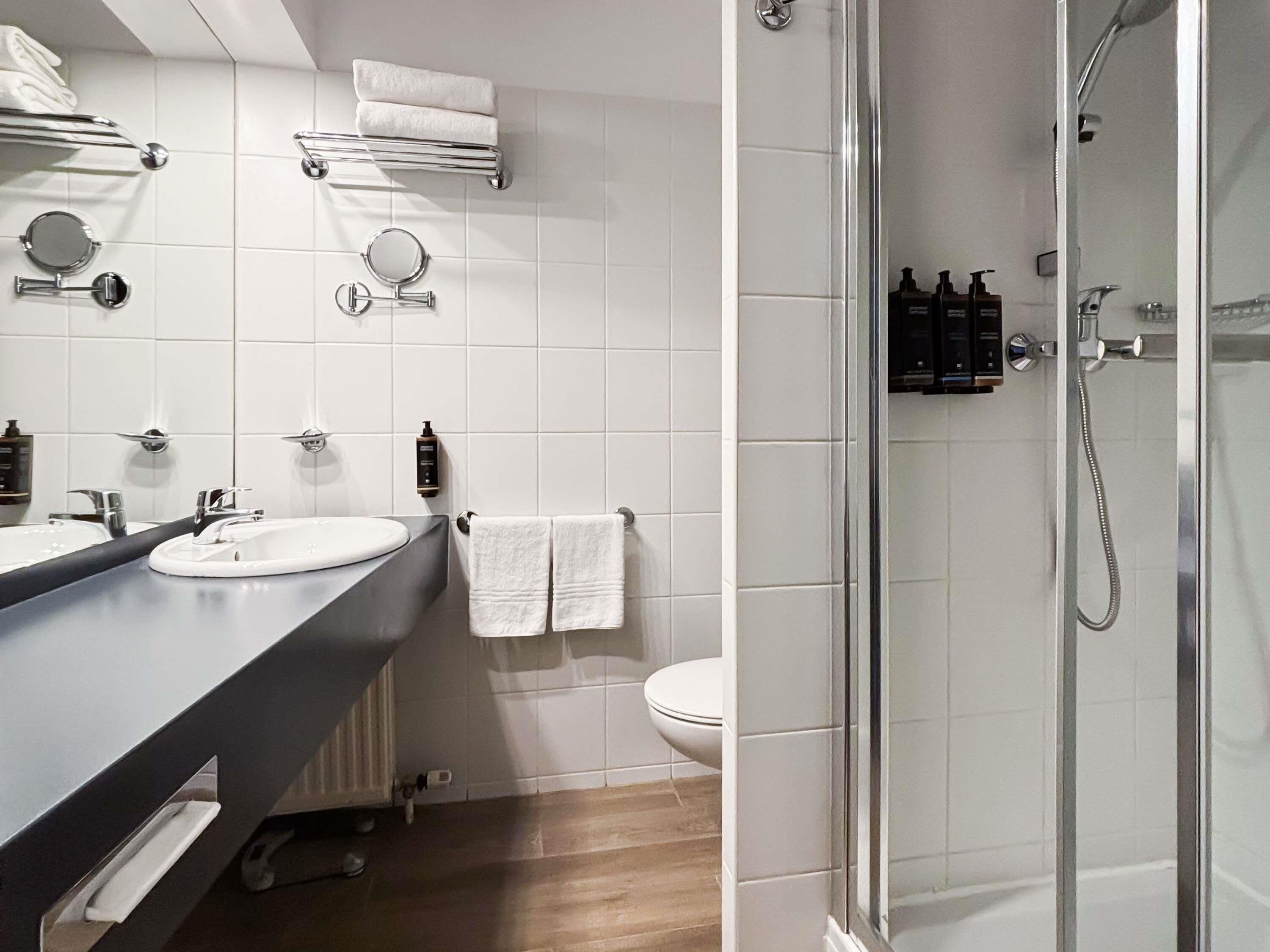 Une salle de bain moderne avec deux lavabos, des toilettes, une douche et un porte-serviettes.
