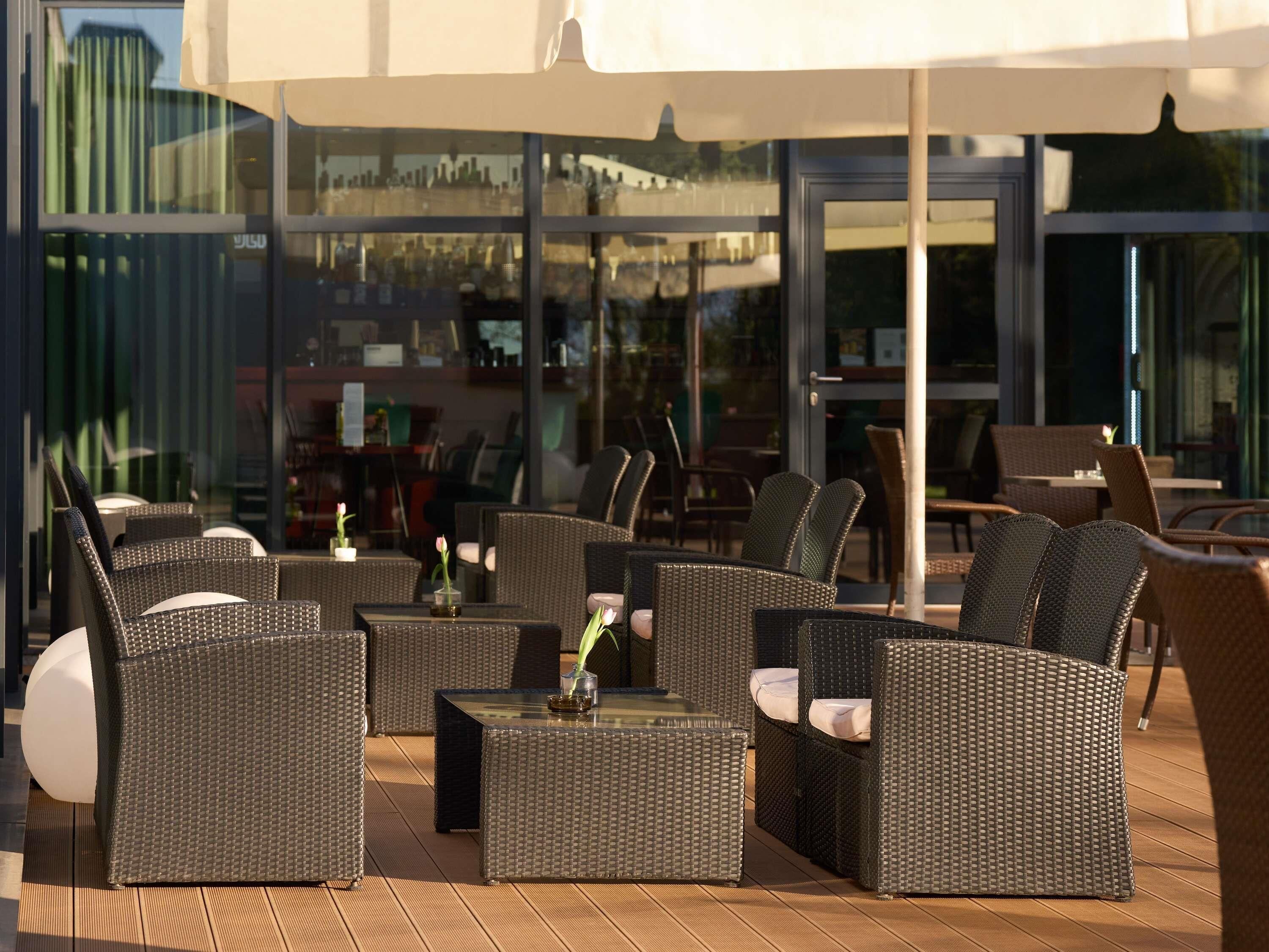 Un espace extérieur aménagé avec des meubles en osier et des tables en verre, offrant une vue sur le paysage urbain.