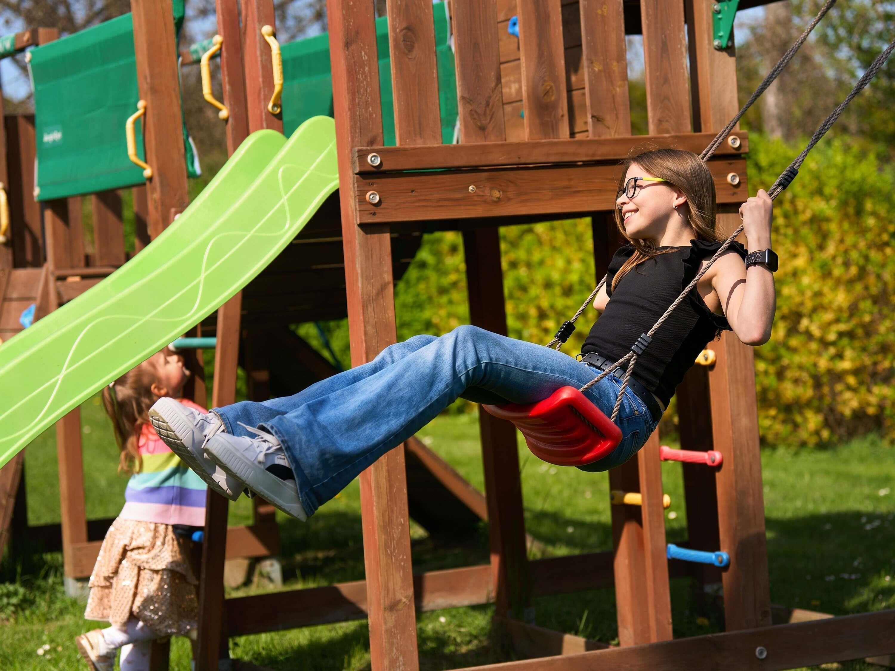 Eine Person schwingt auf einer Schaukel im Spielplatz.