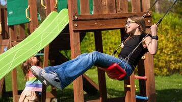 Eine Person schwingt auf einer Schaukel im Spielplatz.