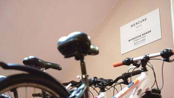 A bicycle with a black seat and handlebars, a white frame, and a pink water bottle.