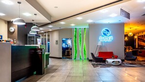A hotel lobby with a reception desk, a clock, and a neon sign for 'KUCHENIA baz grafic'. - Mercure Cieszyn (Cieszyn)