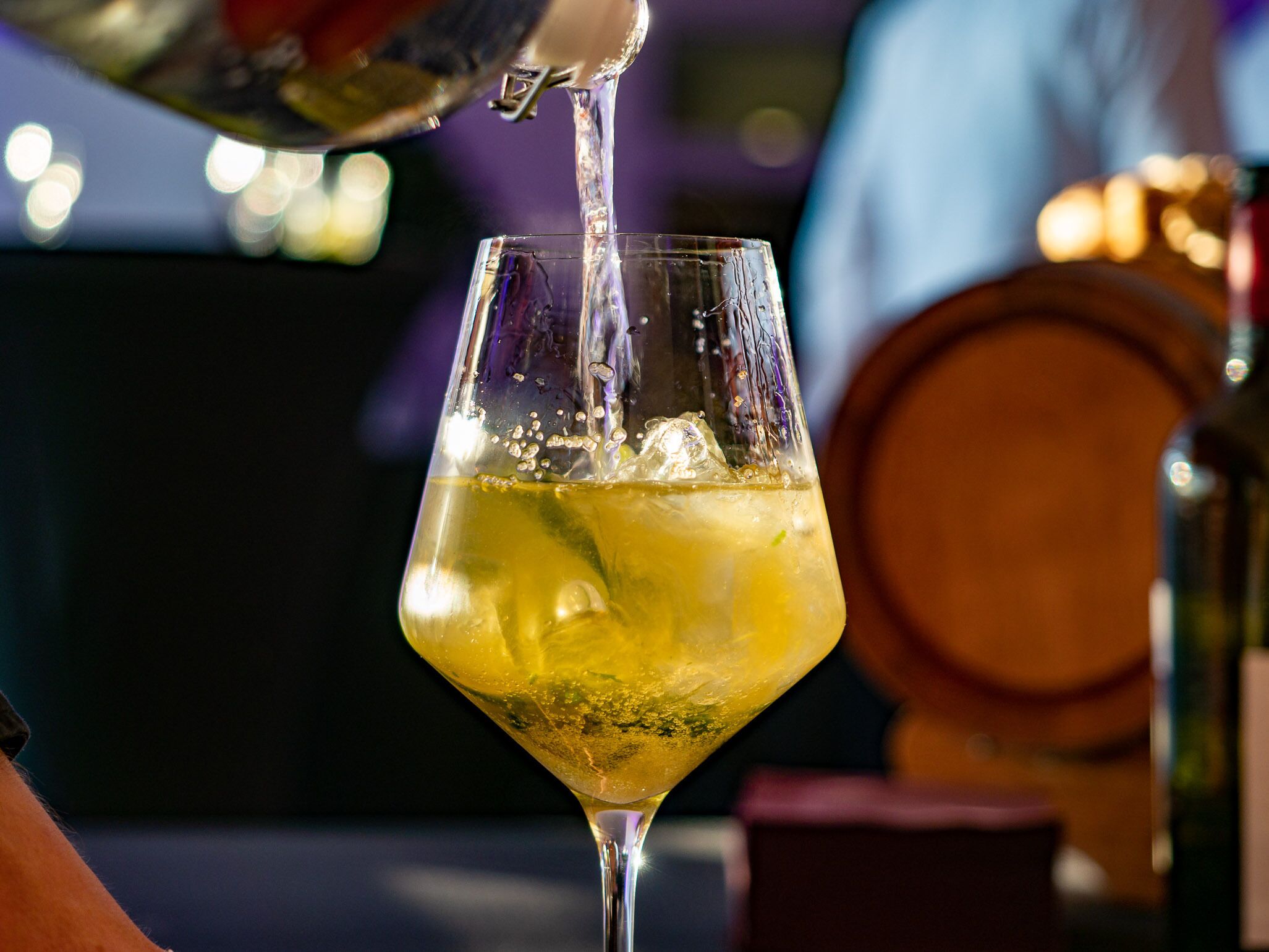 A cocktail being poured into a martini glass.