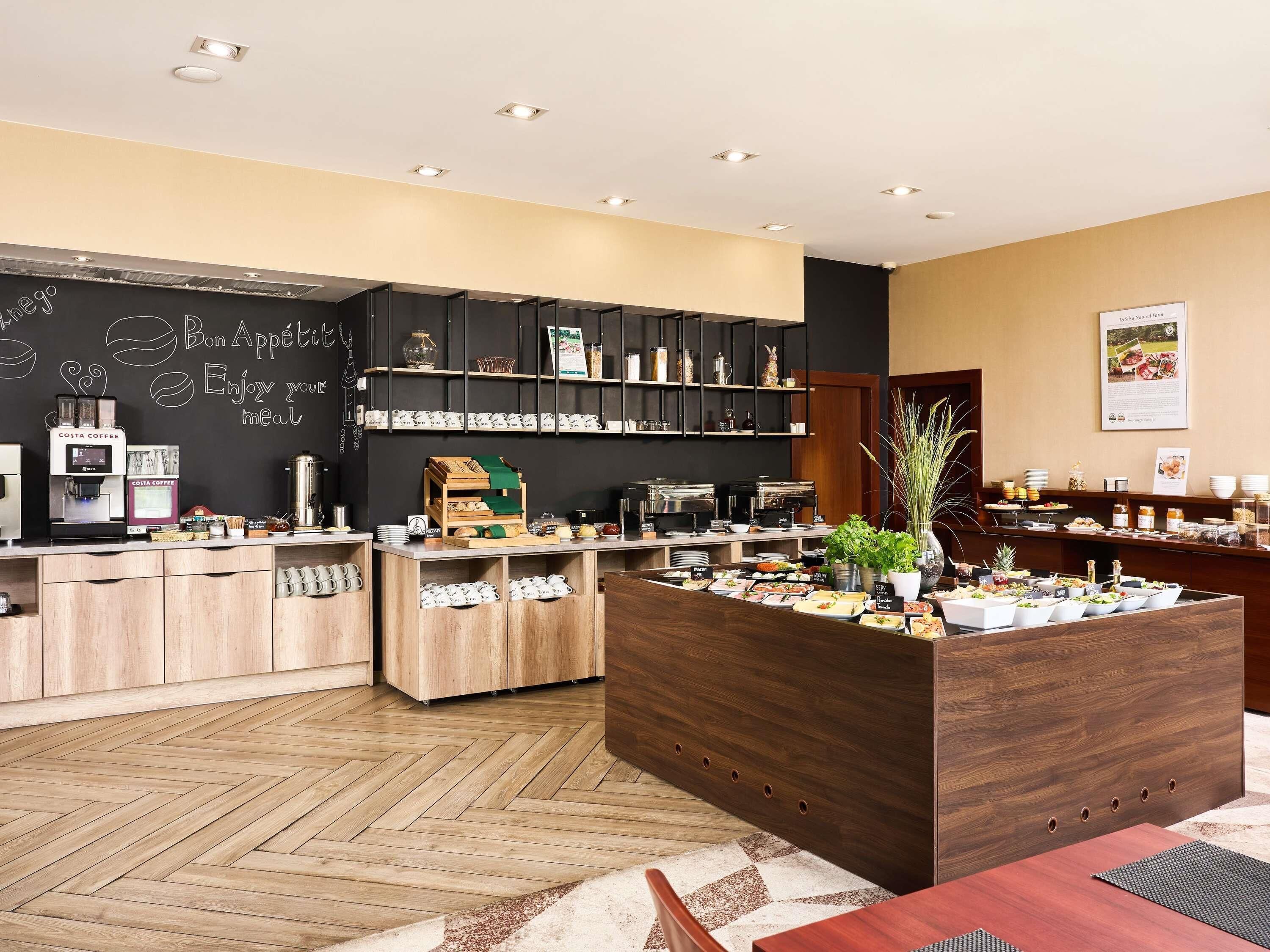 Una barra de desayuno moderna con máquinas de café, un menú en la pizarra y diversas opciones para el desayuno.