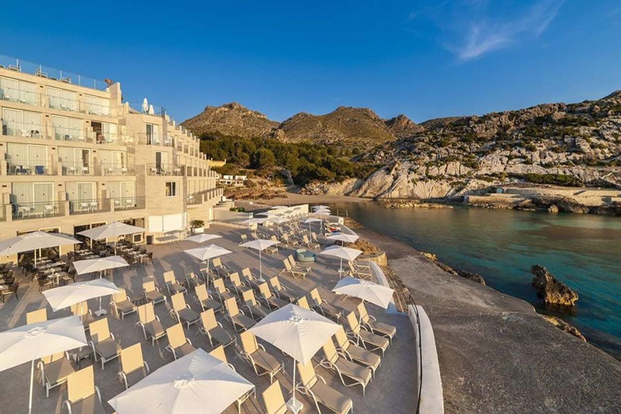 Un hotel con terraza al aire libre y vistas al mar y a las montañas.