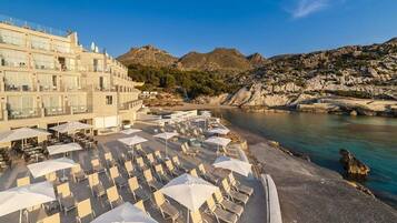 Un hotel con terraza al aire libre y vistas al mar y a las montañas.