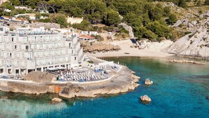Un hotel frente al mar con zona de piscina, acceso a la playa y terreno rocoso.