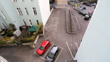 Une vue aérienne d’un parking avec deux voitures, une structure dotée d’un toit végétalisé et un bâtiment avec de nombreuses fenêtres.