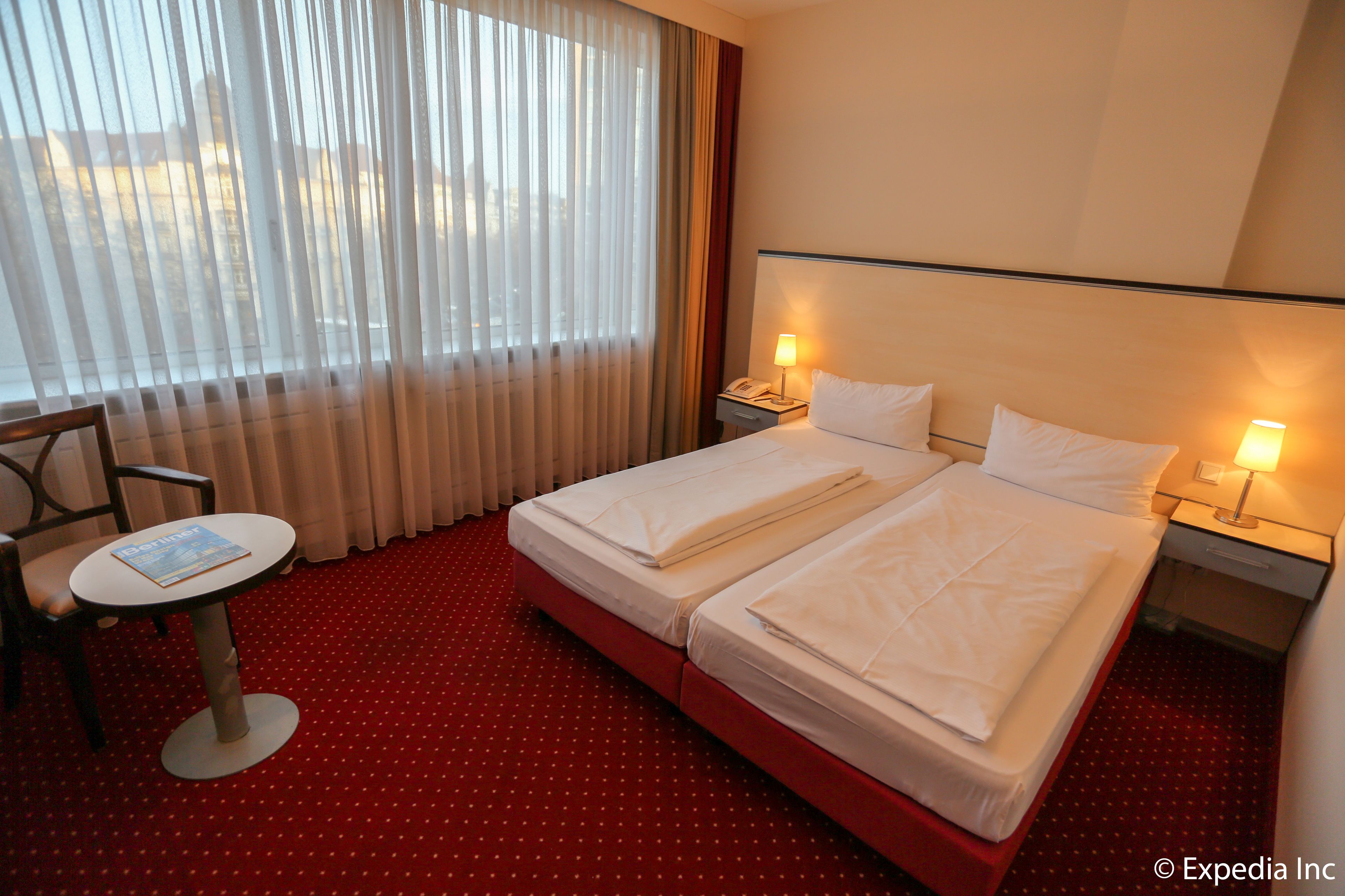 Et hotelværelse med to senge, et lille bord og en stol.