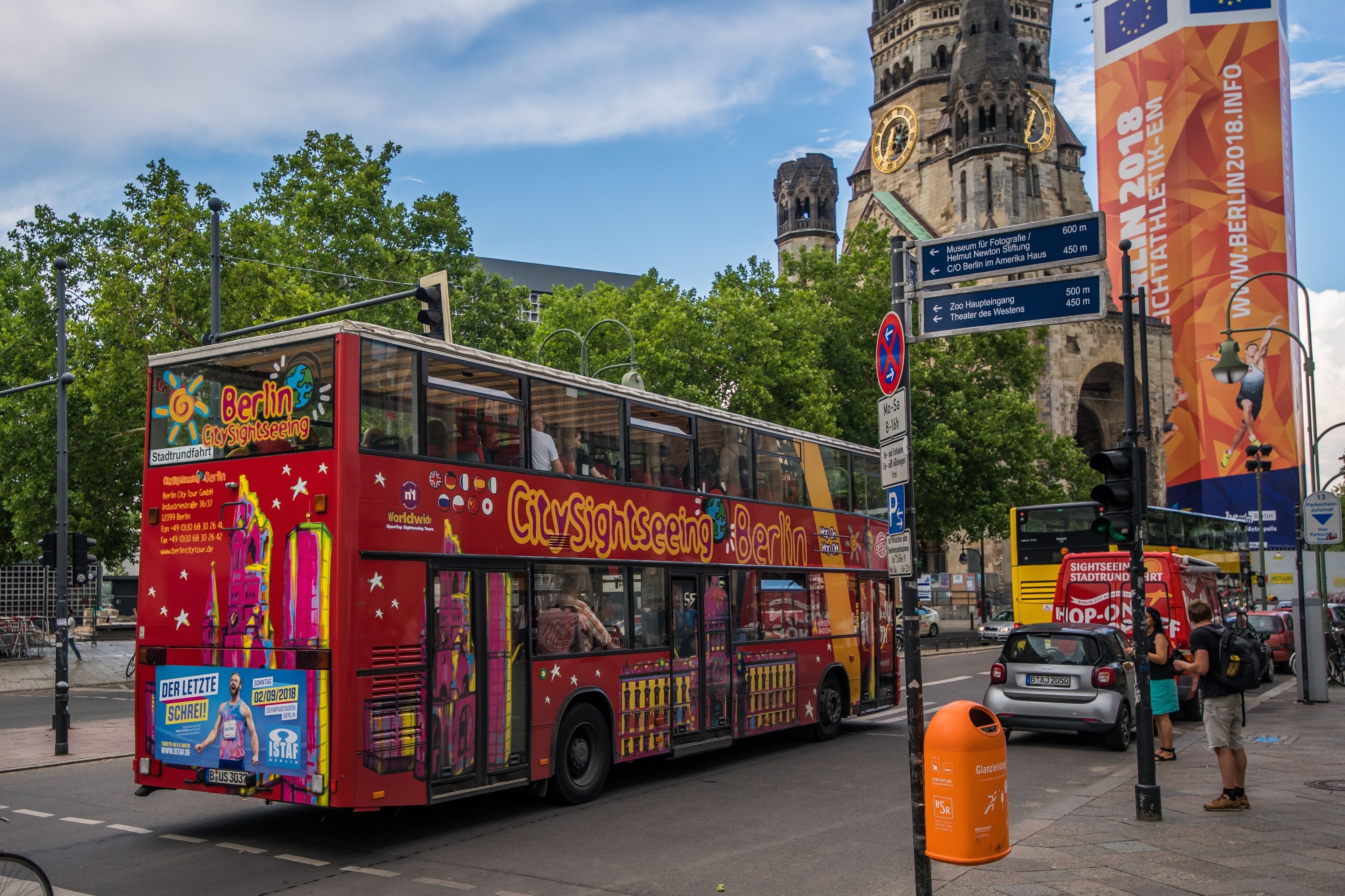 A red double-decker bus with "CitySightseeing Berlin" written on it, parked on a city street.