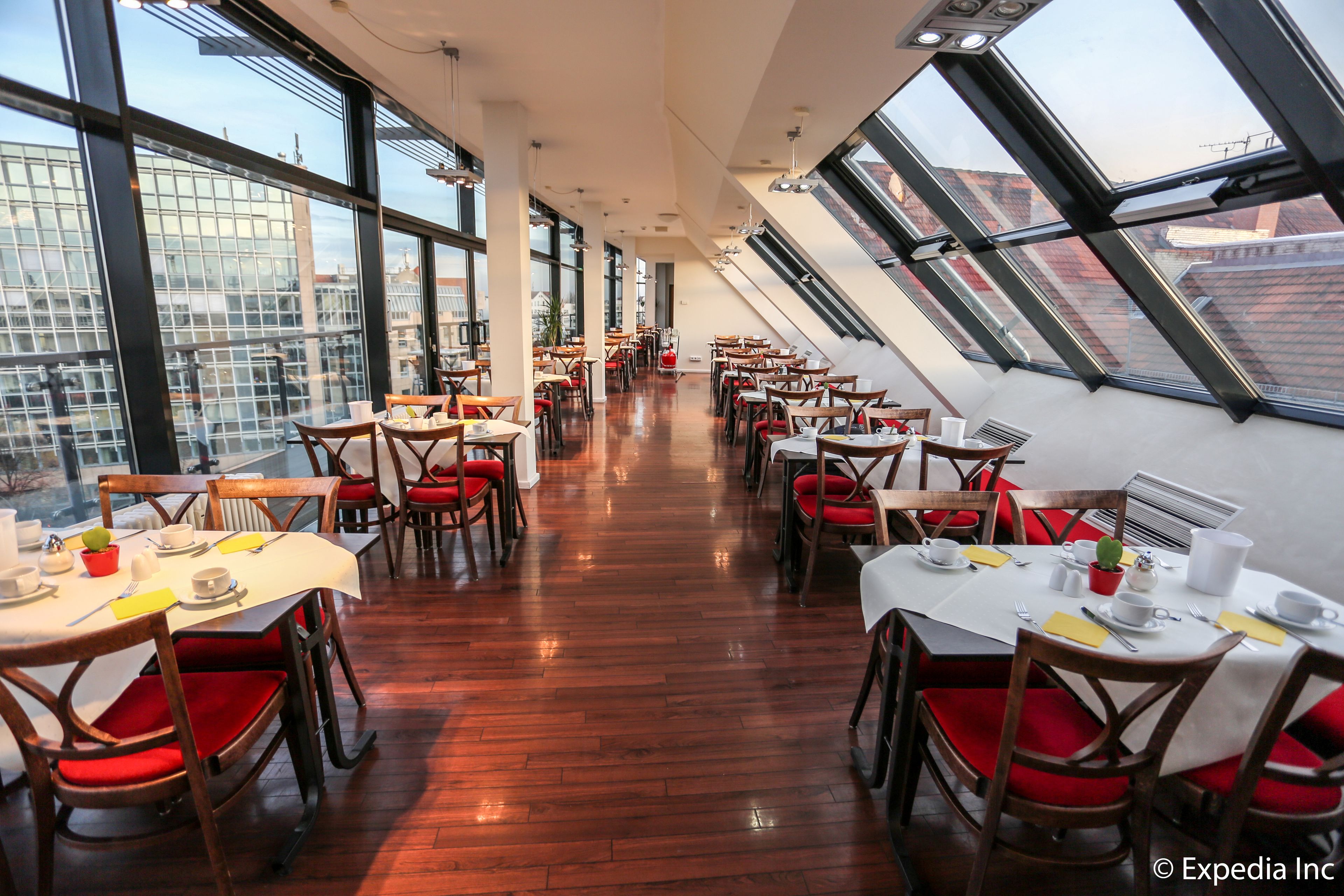 A restaurant with high ceilings, large windows, and a long dining area with tables and chairs.