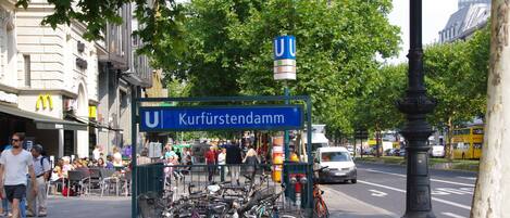 Vista de la calle con un cartel azul que dice "Kurfürstendamm" y un restaurante McDonald's al fondo.