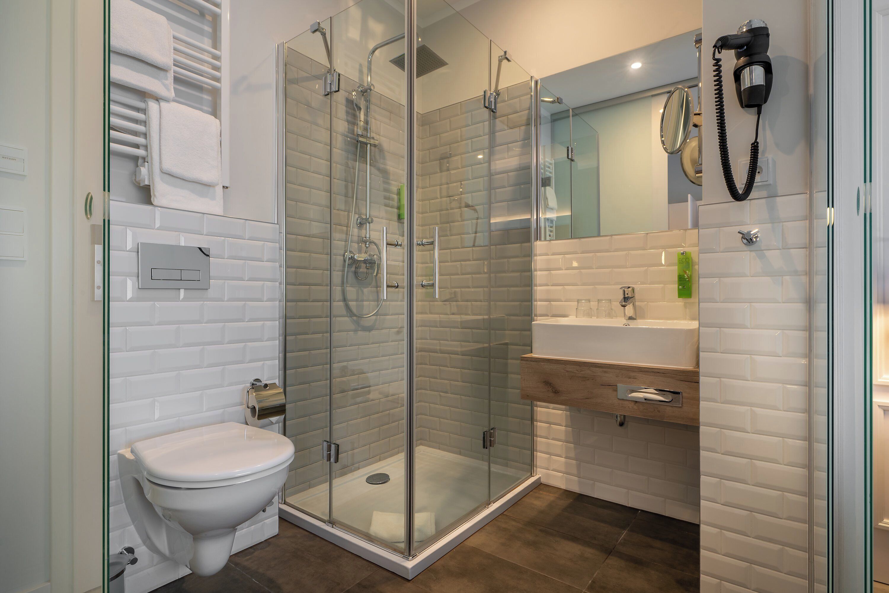 A modern bathroom with a glass-enclosed shower, a toilet, and a sink with a mirror.